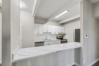Modern kitchen with sleek white cabinetry, marble countertops, and stainless steel appliances, exuding contemporary elegance.