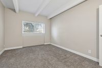 Bright, cozy bedroom with plush carpeting, large window, and neutral walls exuding warmth and comfort.
