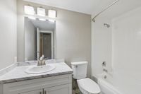 Modern bathroom with elegant marble countertop, stylish vanity, and bright overhead lighting, complementing a sleek white bathtub.