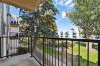 Charming apartment balcony with scenic views of lush green trees and a peaceful neighborhood setting.