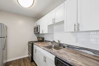 Modern kitchen with sleek stainless steel appliances, elegant marble countertops, and white cabinetry offering ample storage space.