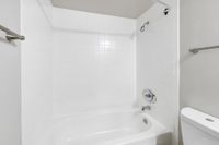 Bright and modern bathroom featuring a pristine white tiled shower and bathtub combo, complemented by sleek fixtures.