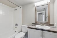 Modern bathroom with elegant design featuring a sleek vanity, well-lit mirror, and pristine bathtub.