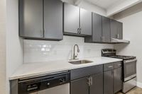 Modern kitchen with sleek gray cabinets, stainless steel appliances, and elegant white subway tile backsplash.