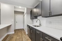 Modern kitchen with sleek dark cabinetry, elegant white countertops, and stylish subway tile backsplash, creating a chic and inviting cooking area.