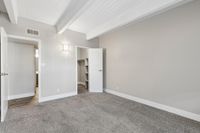 Bright and spacious empty room featuring cozy carpet flooring, an open closet, and modern lighting perfect for customization.