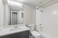 Sleek modern bathroom featuring a pristine white bathtub, contemporary sink, and stylish lighting.