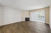 Inviting living room with elegant wood flooring, a charming brick fireplace, and expansive glass doors leading to a serene outdoor view.
