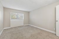 Bright and airy bedroom with plush carpeting and expansive window with blinds, inviting natural light.