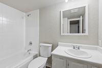 Bright and modern bathroom featuring a sleek white bathtub, matching vanity, and a large mirror.