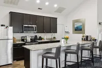 Modern kitchen with sleek dark cabinetry, stainless steel appliances, and a spacious granite island with stylish barstools.