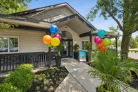 Inviting apartment entrance with vibrant balloons, lush greenery, and a self-guided tour sign, creating a welcoming atmosphere.