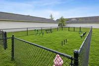 Charming apartment community featuring a fenced dog park with agility equipment and benches, perfect for pet owners.