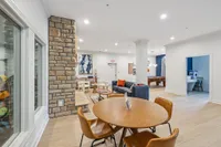 Elegant open-concept living space featuring a cozy seating area, stylish dining table, and modern pool table, perfect for relaxation and entertainment.