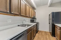 Modern kitchen with sleek countertops, dark wood cabinets, and stainless steel appliances under a beamed ceiling.
