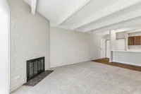 Bright and inviting living area with stylish brick accent wall, cozy fireplace, and seamless access to a sleek kitchen.