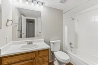 Bright and modern bathroom with sleek vanity, large mirror, and pristine bathtub in a stylish apartment.