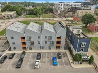 Modern apartment complex with unique angled roofs and vibrant urban surroundings, featuring convenient parking and easy access to nearby amenities.