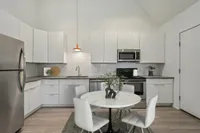 Modern kitchen with sleek white cabinetry, stainless steel appliances, and a cozy dining area.