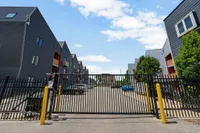 Modern gated apartment complex with sleek architectural design and ample parking space under a bright blue sky.