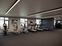 Modern fitness center with state-of-the-art equipment, featuring treadmills, exercise bikes, and large windows for natural light.