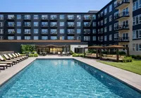 Luxurious apartment complex with a sparkling pool, stylish lounging areas, and modern architecture, perfect for a vibrant lifestyle.