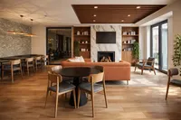 Elegant and modern living area with a cozy fireplace, plush orange sofa, wooden bookshelves, and chic dining space.