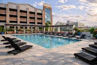 Luxurious outdoor pool area with sleek lounge chairs, modern pergolas, and lush greenery, set against a stylish urban building backdrop.