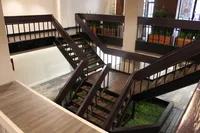 Chic industrial-style staircase with sleek wooden railings, surrounded by lush indoor greenery for a modern apartment ambiance.