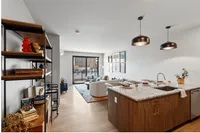 Modern open-concept living room and kitchen with elegant decor, featuring a cozy seating area and stylish lighting fixtures.