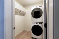 Contemporary laundry area featuring a stacked washer and dryer with ample shelving space in a sleek, compact design.