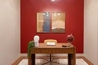 Chic home office featuring a stylish wood desk, vibrant red accent wall, and modern decor elements including a globe and abstract art.