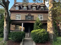 Charming vintage brick building with lush greenery and inviting front porch, exuding character and curb appeal.