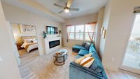 Chic and inviting living room with a plush blue sectional, modern fireplace, and ocean view. Adjacent cozy bedroom with stylish decor.