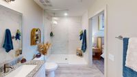 Luxurious modern bathroom with elegant marble shower, stylish vanity, and cozy bedroom view.