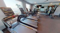 Modern apartment fitness center with state-of-the-art treadmills, overlooking scenic views through large windows.