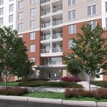 Modern apartment building with red brick facade, lush landscaping, and inviting entrance.