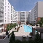 Modern apartment complex with stunning outdoor pool surrounded by lush greenery and lounge chairs, offering luxurious urban living.