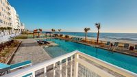 Luxurious beachfront apartment view featuring a sparkling pool and palm-lined oceanfront, perfect for a serene coastal lifestyle.