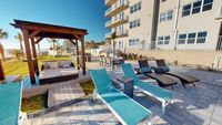 Luxurious outdoor lounge area with modern sun loungers, a cozy gazebo, and stunning ocean views, perfect for relaxation and entertaining.