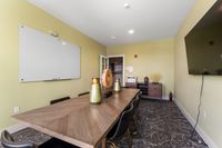 Elegant conference room featuring a modern wood table, stylish decor, and a large flat-screen TV.