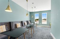 Modern lounge area featuring elegant pendant lighting, stylish gray seating with accent cushions, and abundant natural light from large windows.
