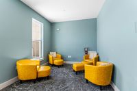 Inviting corner lounge with vibrant yellow chairs against a soothing teal wall, perfect for relaxation.