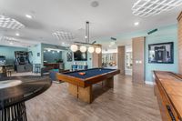 Vibrant entertainment area featuring a sleek pool table, basketball arcade game, and cozy seating under stylish lighting.