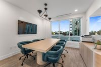 Modern conference room with a sleek wooden table, six plush teal chairs, and a large window offering a bright, spacious atmosphere.