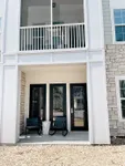 Charming patio with modern rocking chairs in front of elegant double doors, accented by stylish stone wall and large windows.