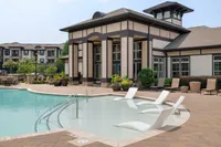 Chic apartment complex with a resort-style pool and comfortable lounging chairs.