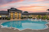 Inviting swimming pool in front of a stylish building, under a vibrant sunset sky.