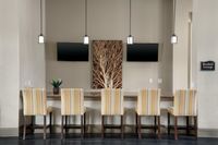 Chic resident lounge with a row of stylish chairs, dual mounted TVs, elegant pendant lighting, and modern decor.