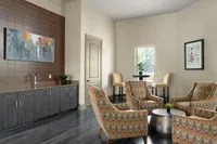 Chic living room with four stylish patterned chairs, a modern art piece, and elegant wooden cabinetry.